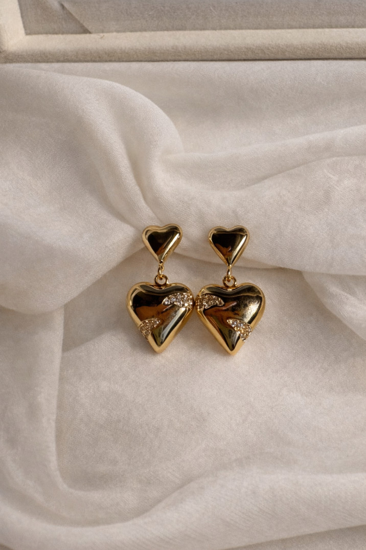 Golden heart-shaped earrings on silk