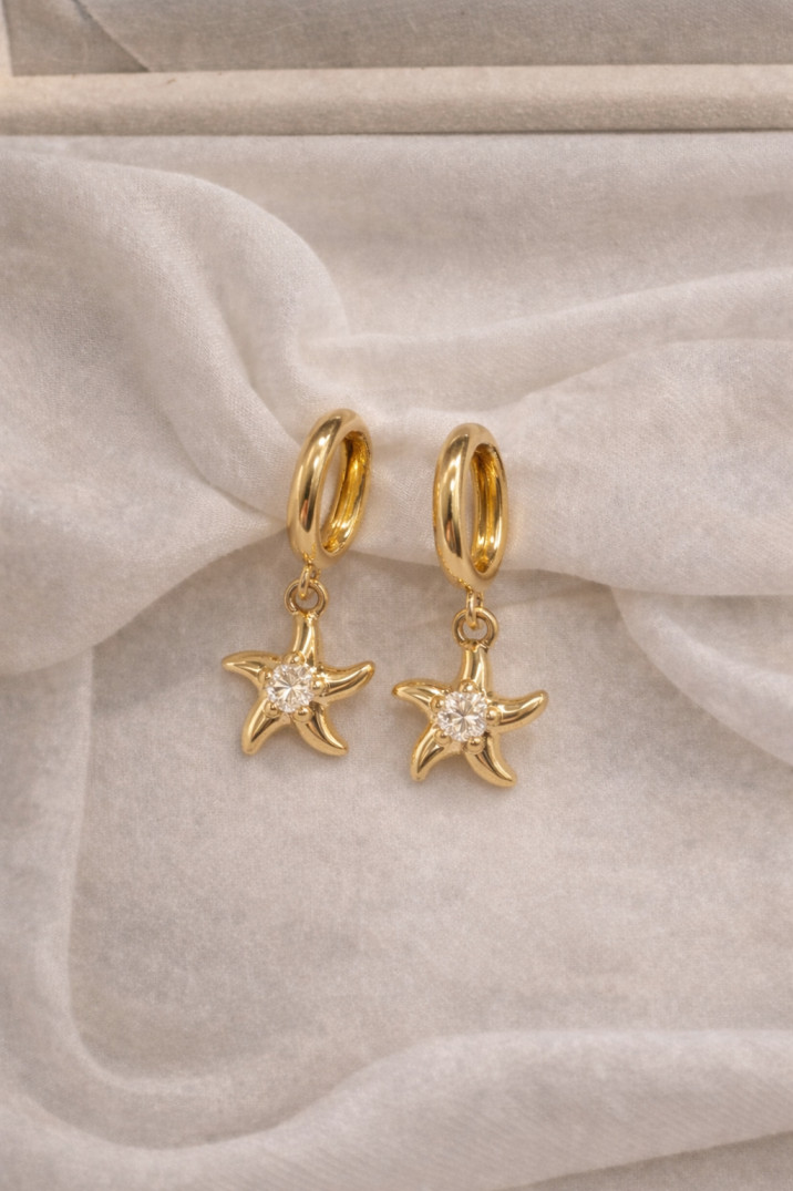 Gold starfish earrings on ivory fabric